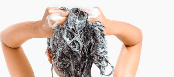 Frau wäscht sich die Haare mit Waschseife